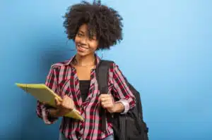 Moça negra com cabelo afro, muito feliz por ter concluído o curso de negócios imobiliários.